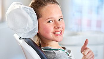 Young girl giving thumbs up in dental chair