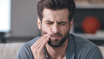 Man holding the side of his cheek in pain
