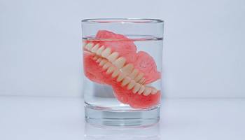 Dentures in glass of clear liquid