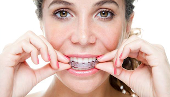 Woman putting on clear aligner in Danville