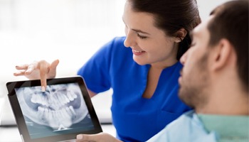 Male dental patient looking at x rays with his dentist