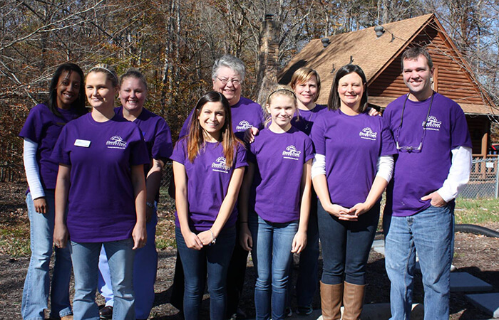 Dr. Payne smiling for a photo with kids in their purple T-shirts