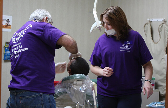 Dental volunteers working on young man in chair