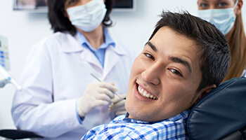 Man in checkered shirt smiling in dental chair
