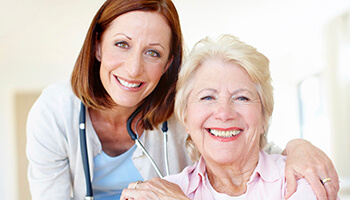 Dentist and elderly patient smiling with dentures in Danville