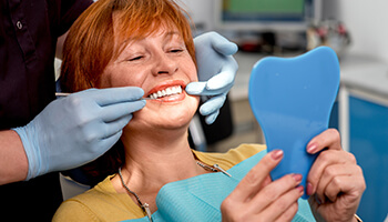 Female patient viewing her teeth in hand mirror