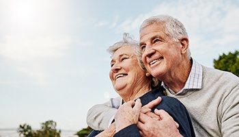 Senior couple smiling while hugging outside
