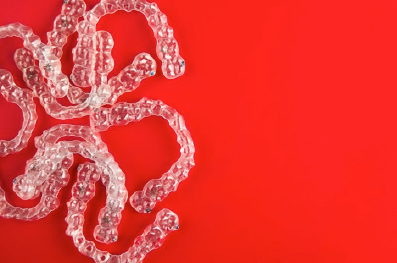 Several Invisalign clear aligners on red background