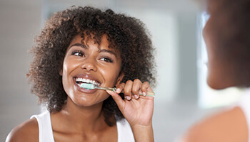 Young woman brushing teeth in mirror in Danville