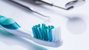 Toothbrush and dental mirror lying on a flat surface