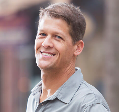 Man in gray collared shirt smiling