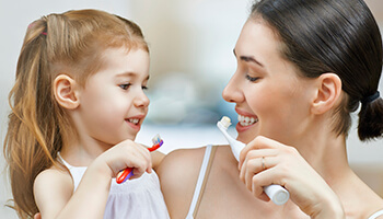 Mother and daughter brushing teeth