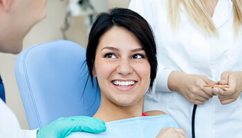 Young patient in dental chair talking with her dentist