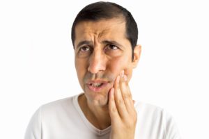 man holds jaw painfully from toothache