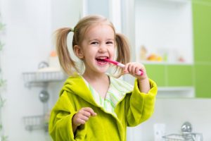 young girl smiling brushing her teeth