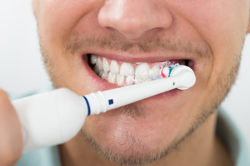 close-up of man using electric toothbrush