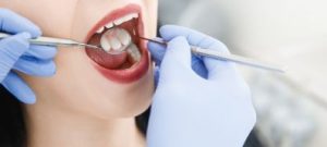 Dentist performing a gum exam on female patient