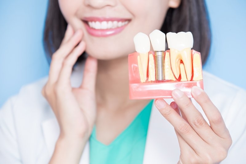 dentist holding model of dental implant