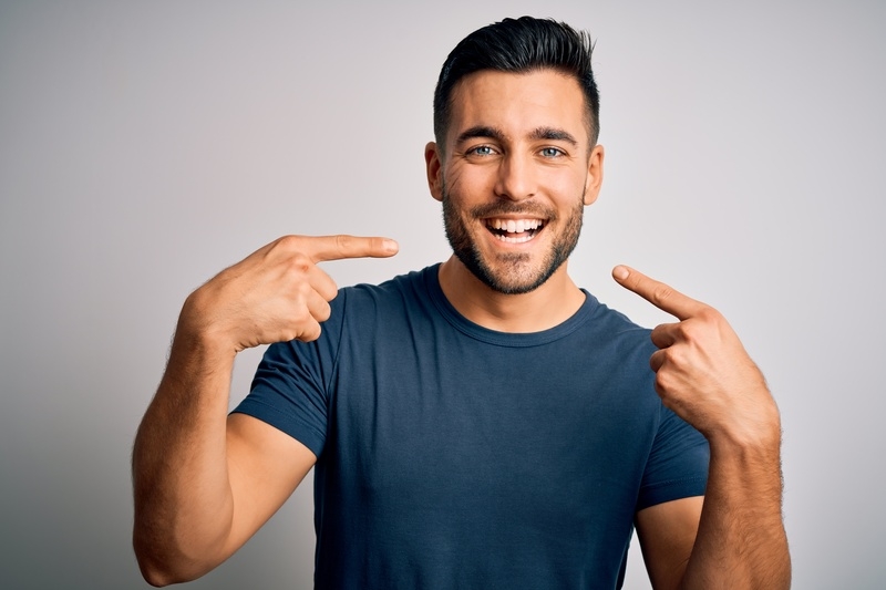 Young smiling man pointing at his smile.