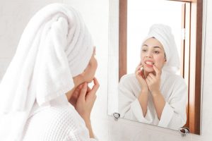 A woman inspecting her teeth in the bathroom mirror.