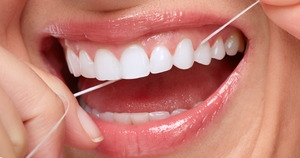 Close-up of person smiling and flossing their teeth