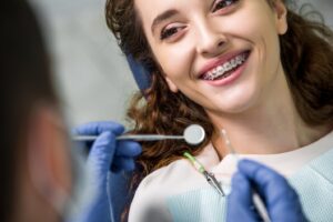 Adult woman with braces getting treated in dentist’s chair.